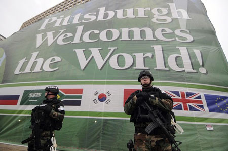 Security personnel stand guard in front of a welcome banner on the Hilton Hotel in downtown Pittsburgh, Pennsylvania, on the first day of the G20 Summit, September 24, 2009